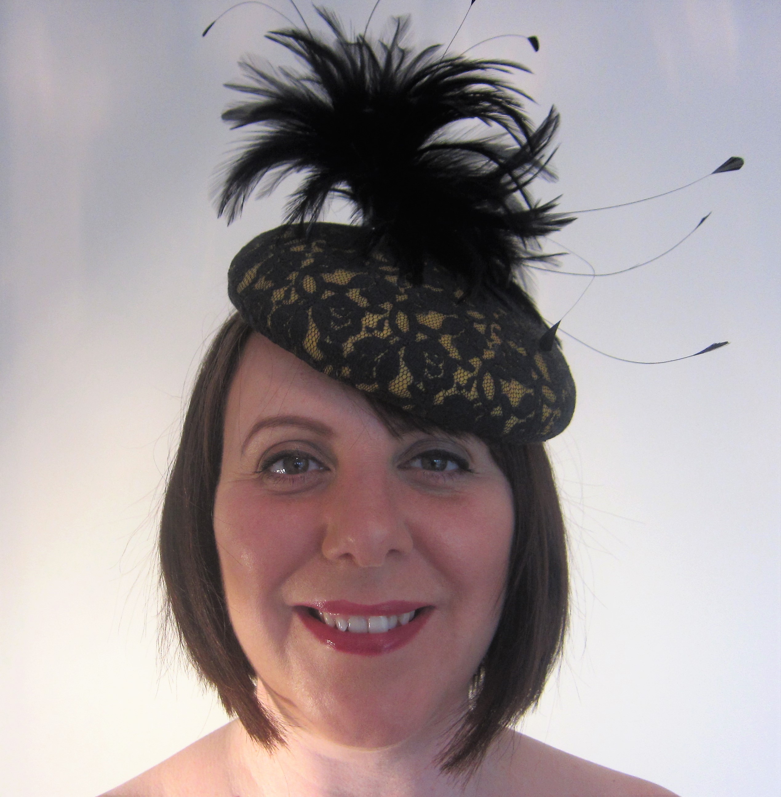 Yellow felt button with black lace and attractive black feather mount.